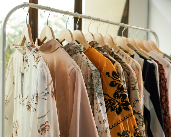 Rack of clothes with various garments on hangers in a well-lit room.